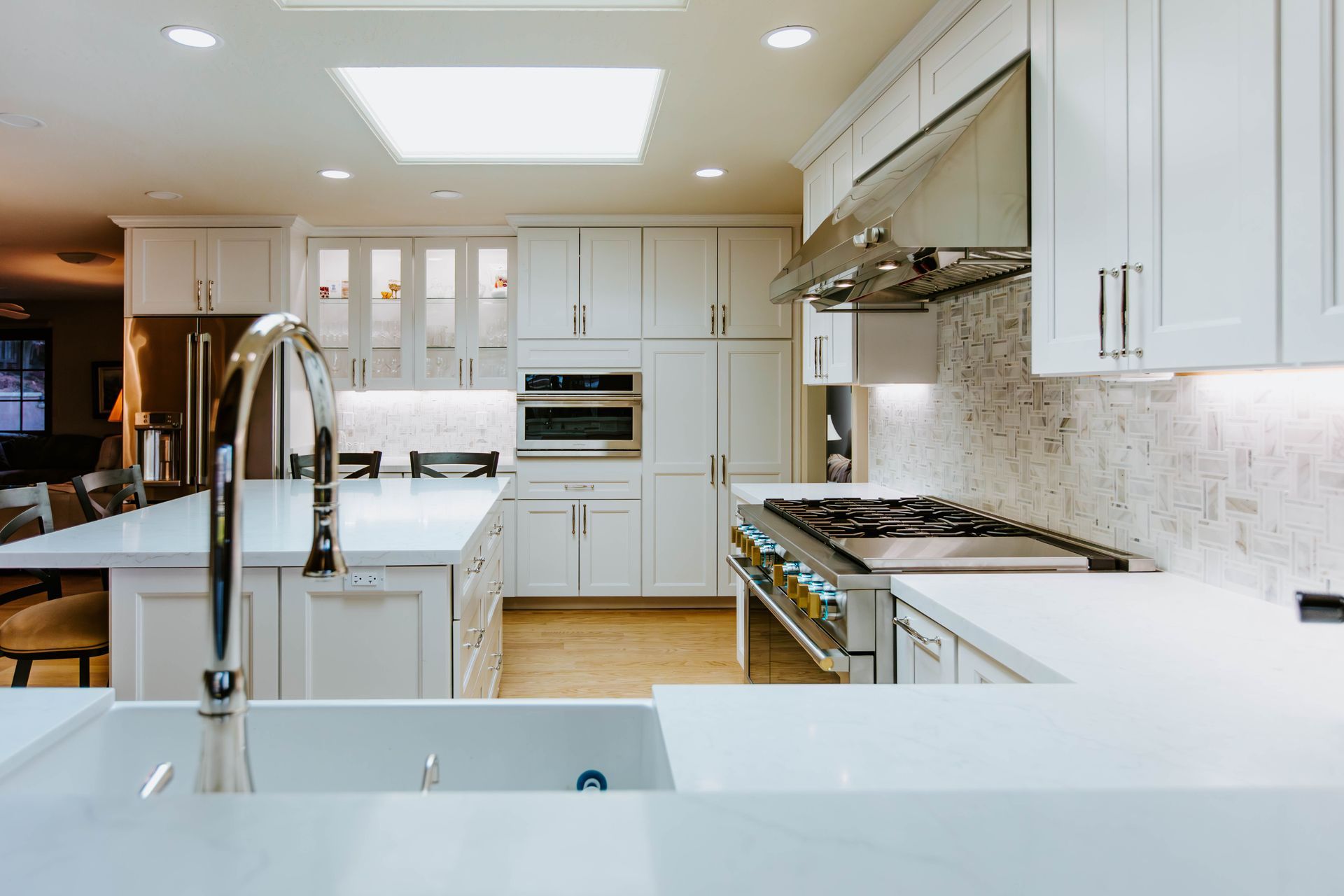 A kitchen with white cabinets , stainless steel appliances , a sink and a stove.