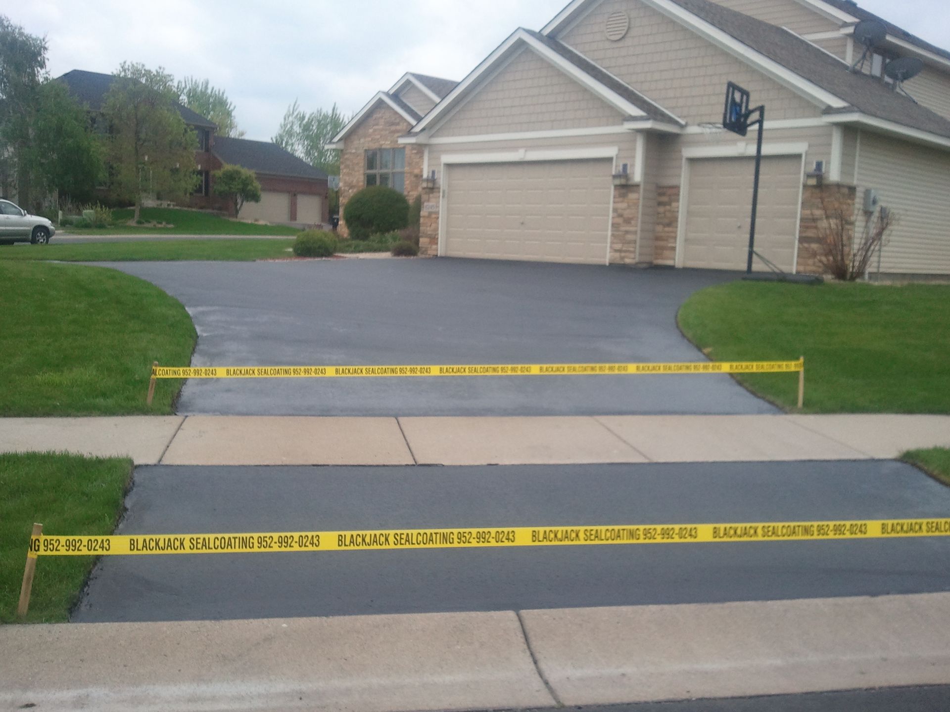 Driveway and sidewalk blocked by yellow caution tape in front of a suburban house.