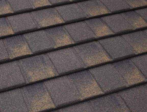 Close-up of dark gray asphalt shingles on a roof, textured and weathered.