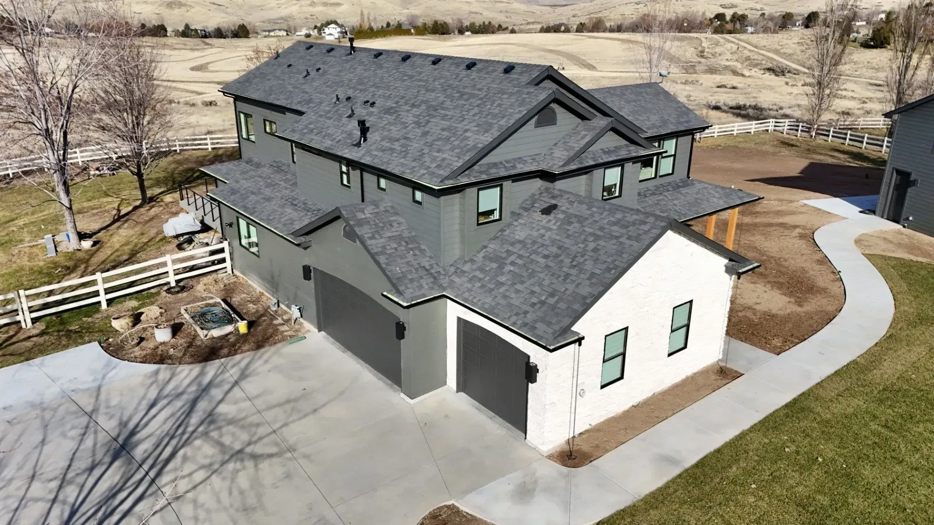 Two-story modern home with gray and white exterior, two-car garage, and winding concrete path.