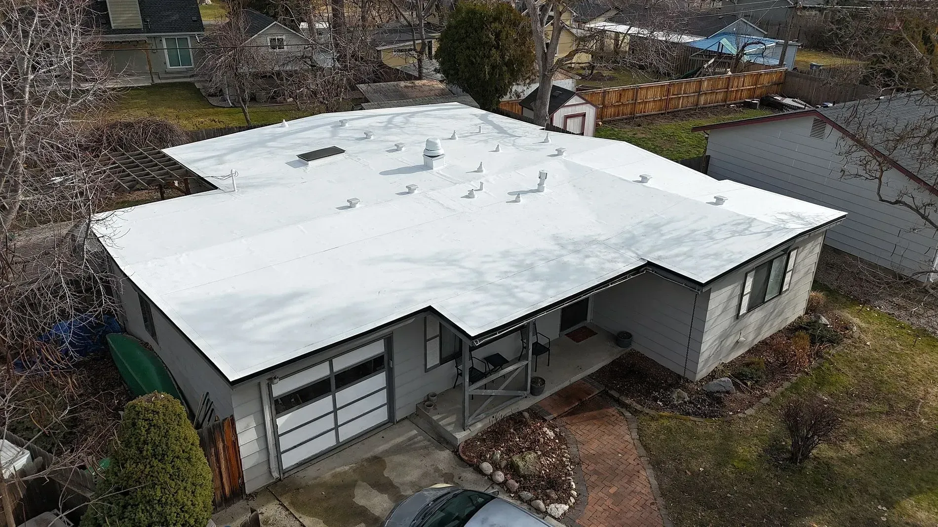 An aerial view of a gray house with a white roof covered in snow.