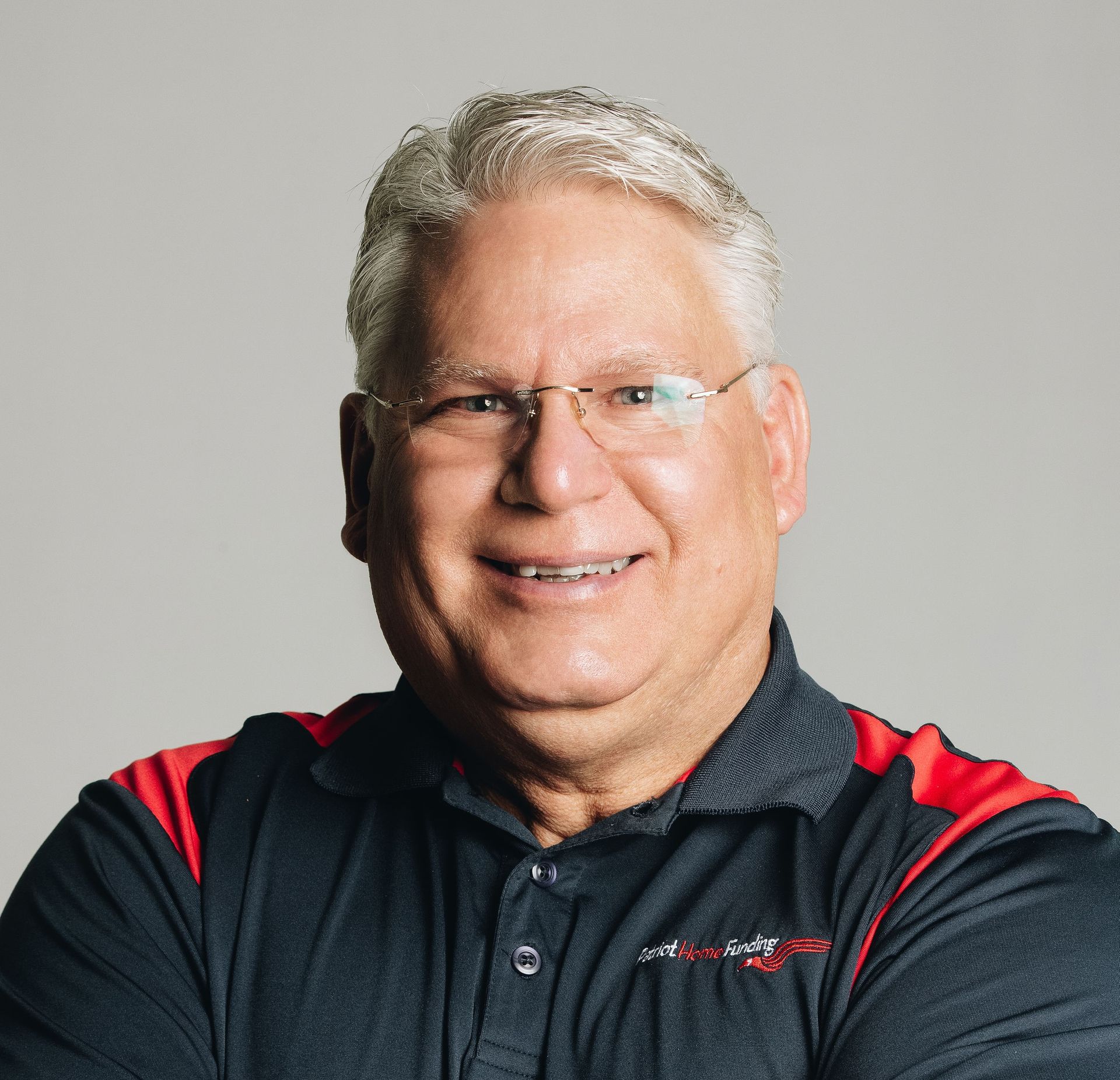 A man wearing glasses and a black and red shirt is smiling for the camera.