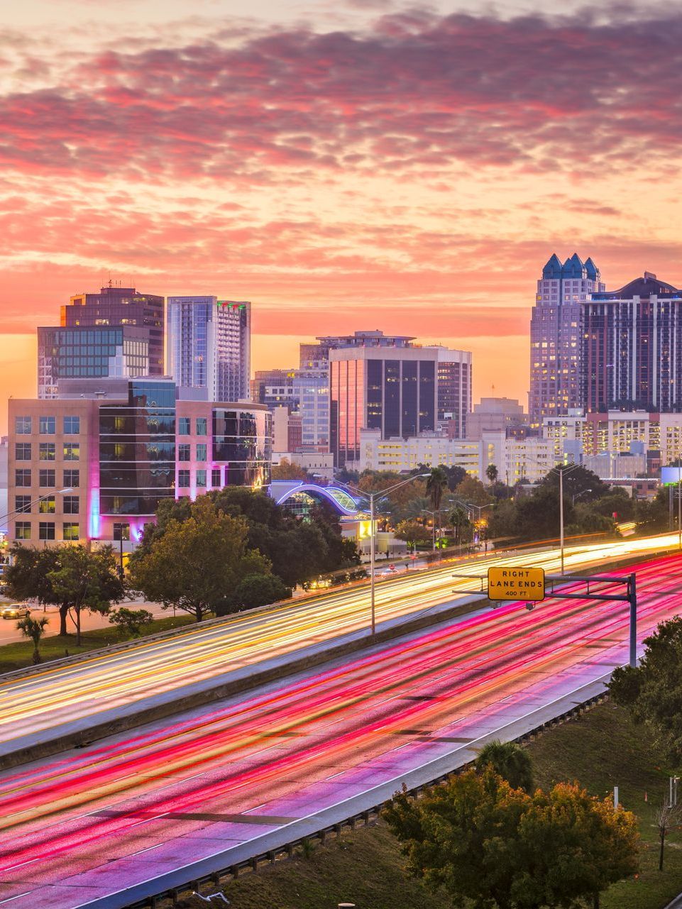 An aerial view of a highway leading to a city at sunset.