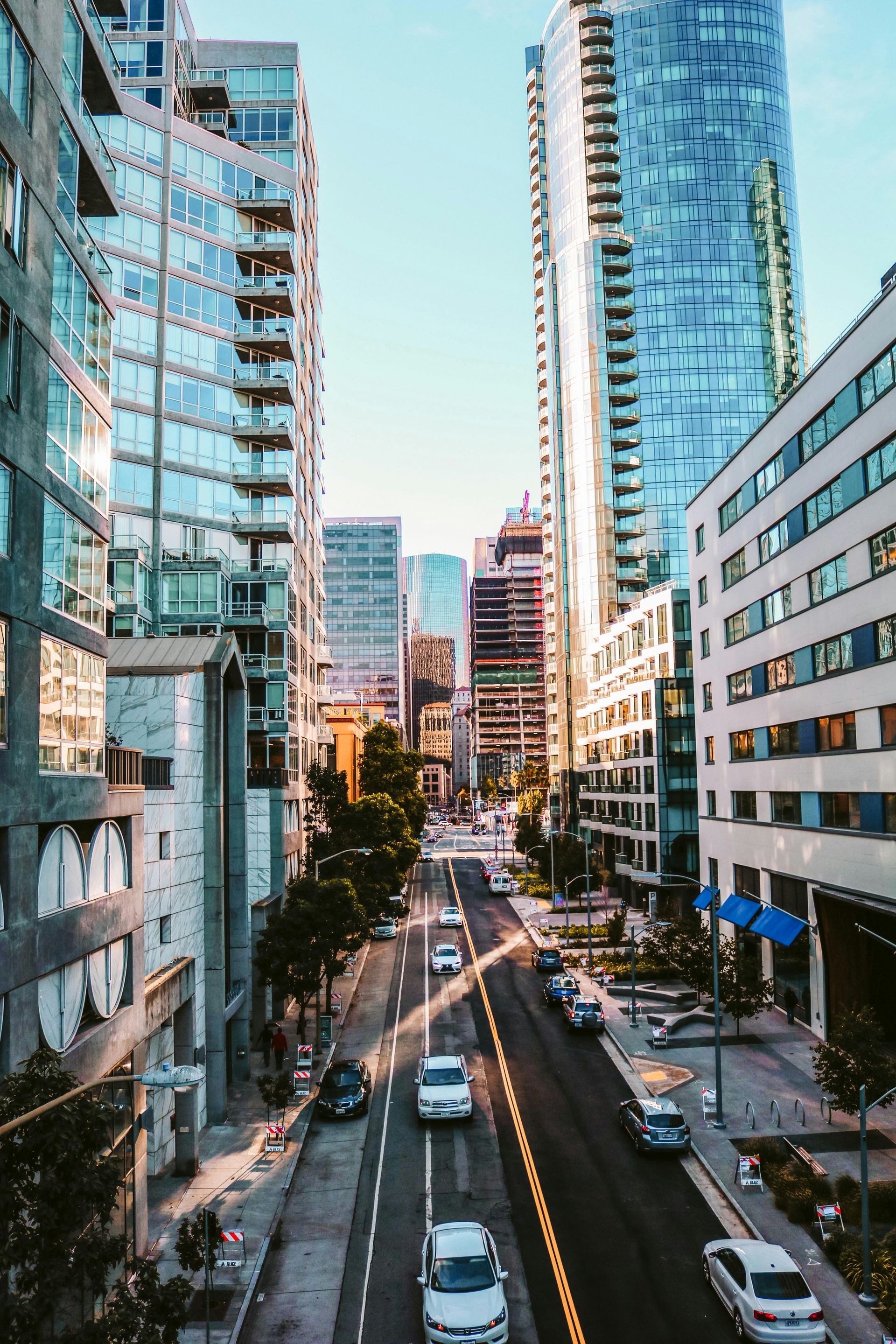 A city street with a lot of tall buildings and cars driving down it.