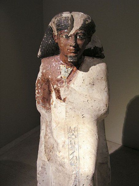 A statue of a man with a crown on his head is standing in a dark room.