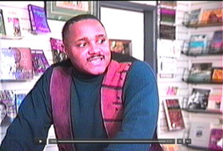 A man is standing in front of a bookshelf in a store.