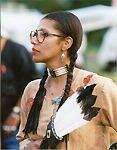 A woman wearing glasses and a choker is standing in front of a tent.