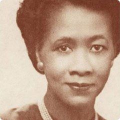 A black and white photo of a woman wearing a pearl necklace.