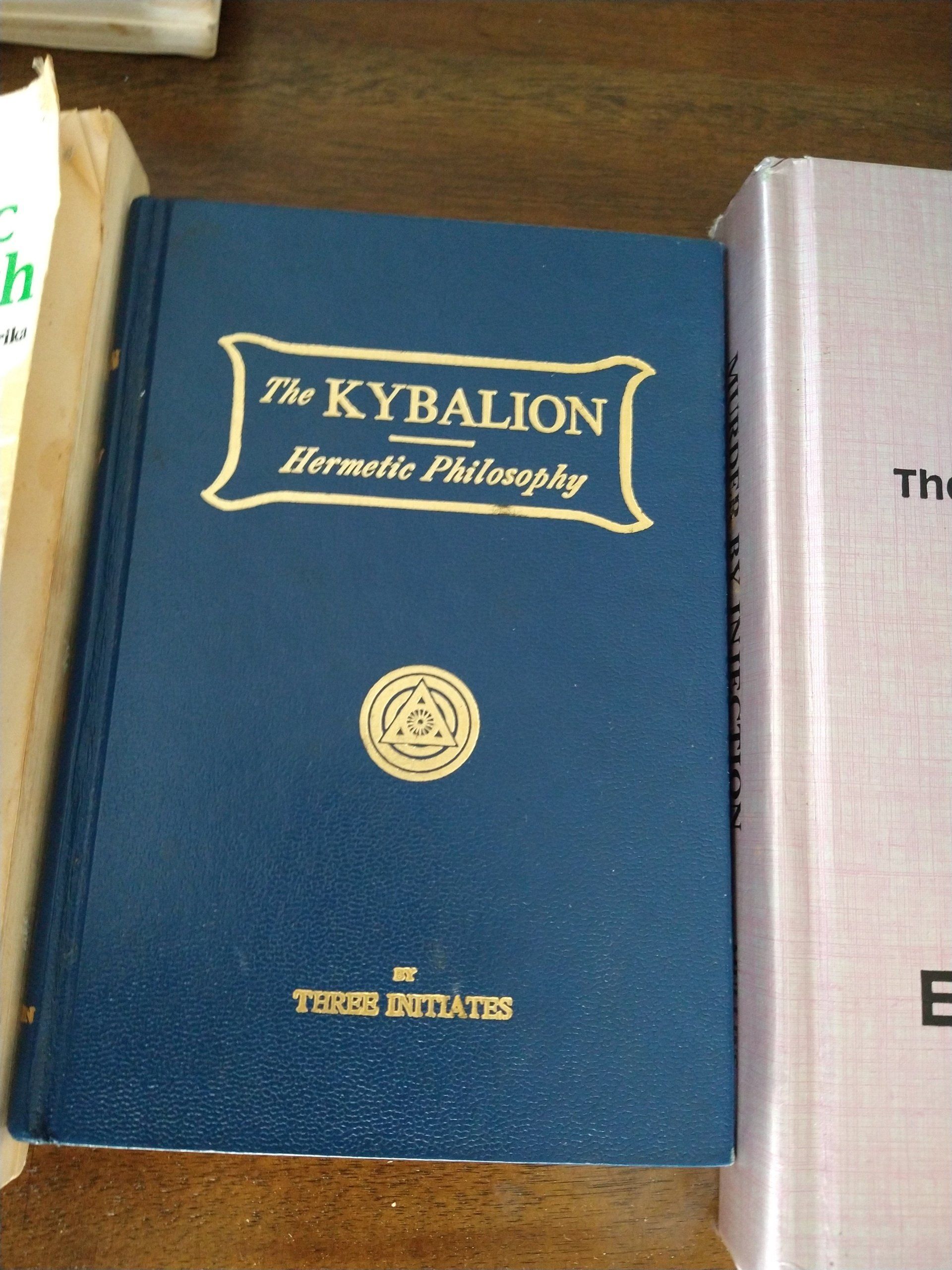 A blue book titled the kybalion sits on a table