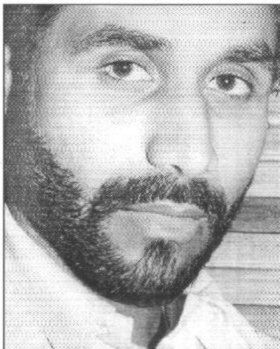 A man with a beard is looking at the camera in a black and white photo.