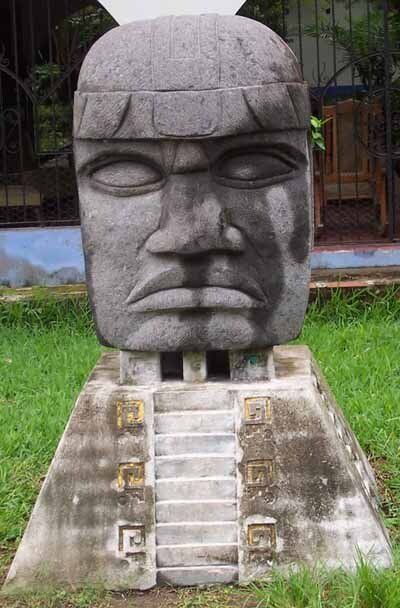 A large stone statue of a man 's head is sitting on top of a pyramid.