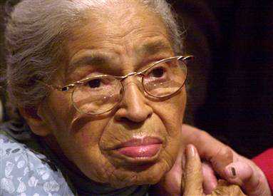 An elderly woman wearing glasses is being held by a person.