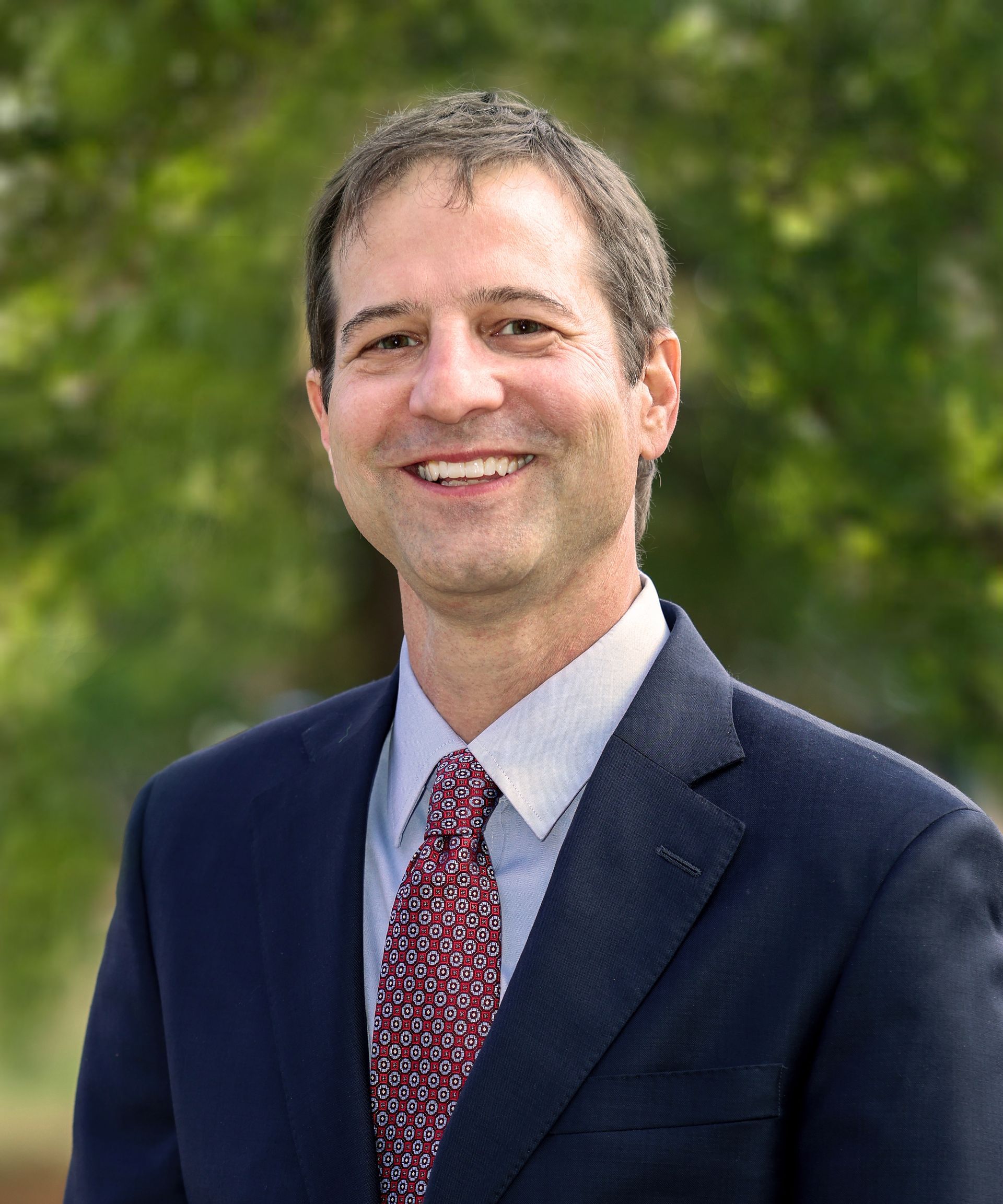 A man in a suit and tie is smiling for the camera.