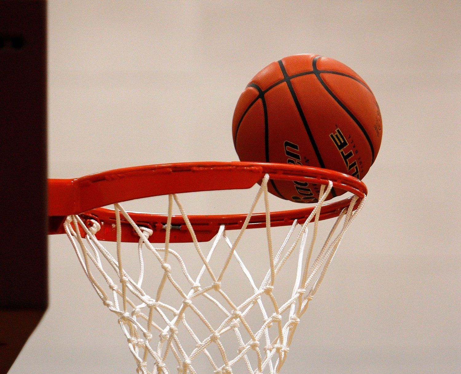 A spalding basketball is going through a hoop