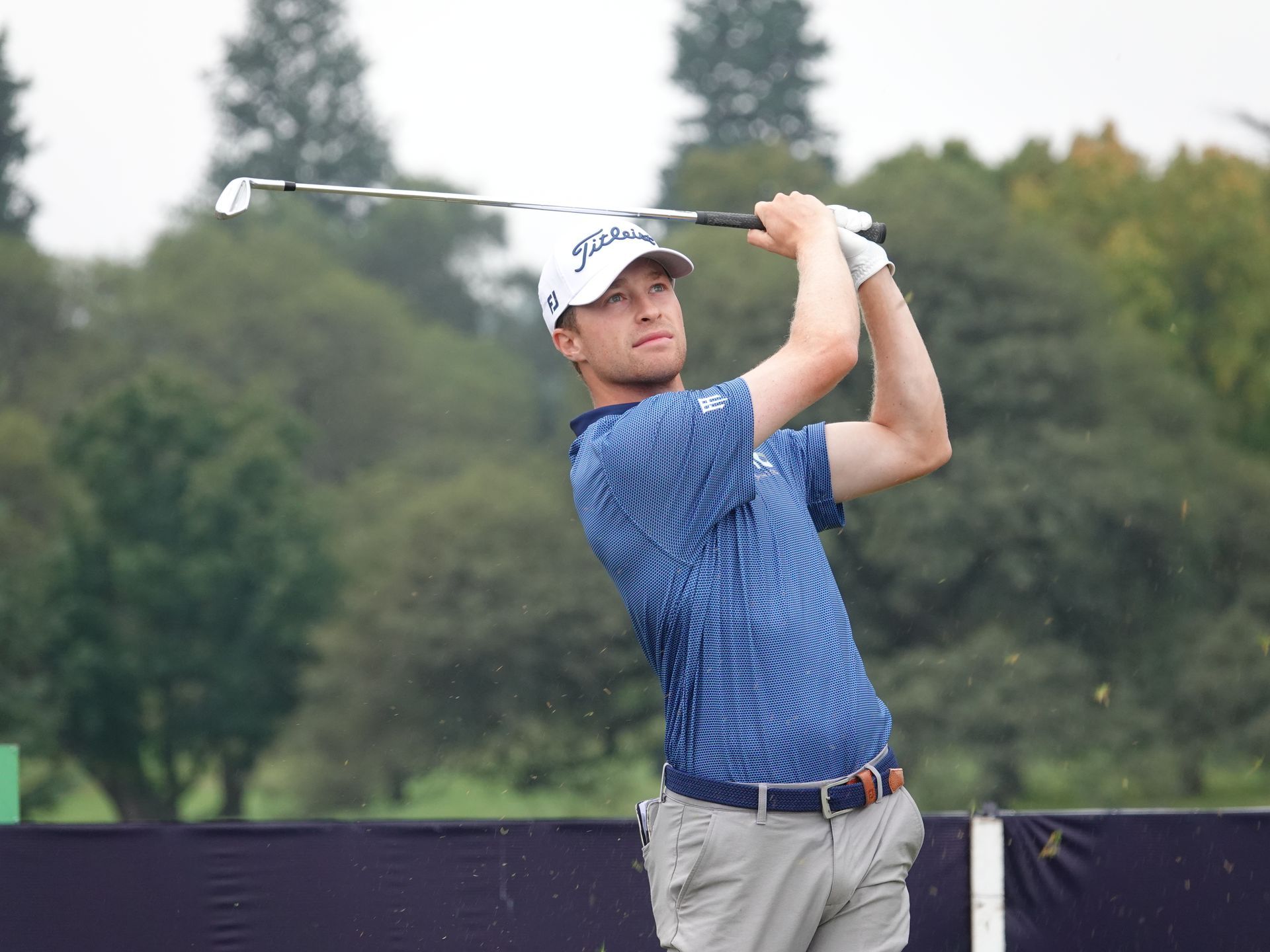 A man is swinging a golf club on a golf course.