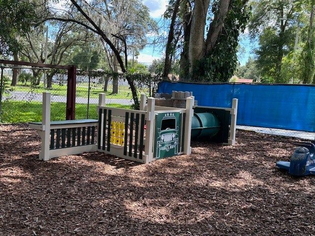 A playground with a fence and a tunnel in the middle of it.