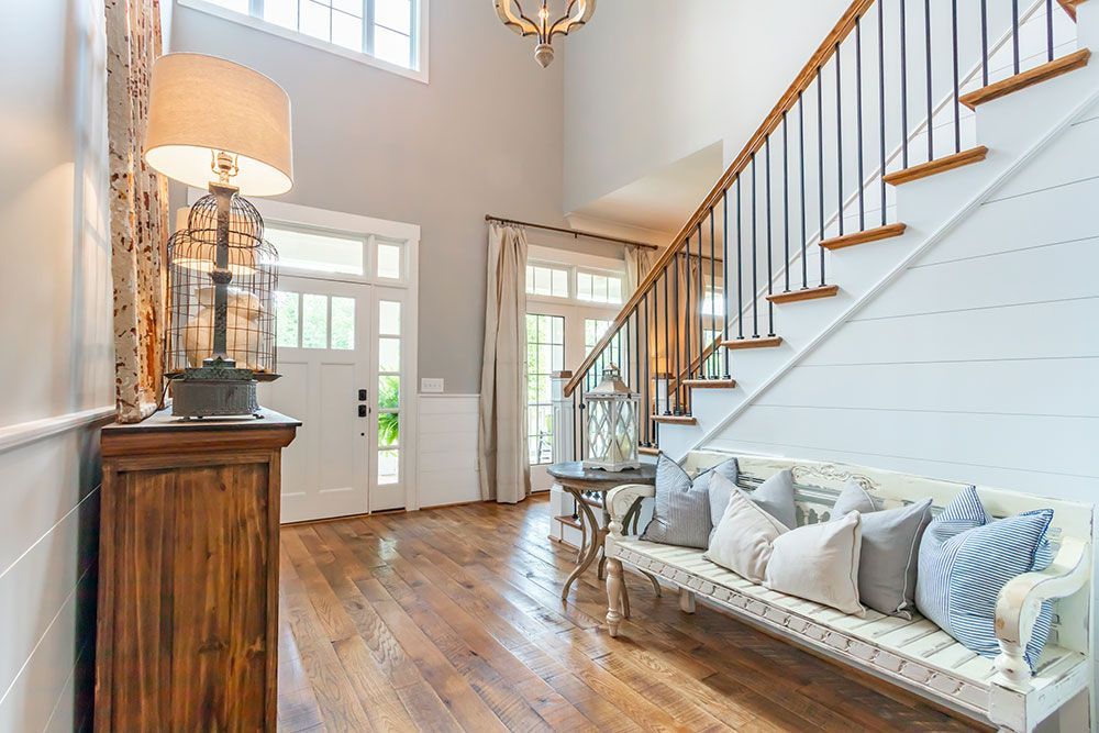 A hallway with a bench and stairs in a house.