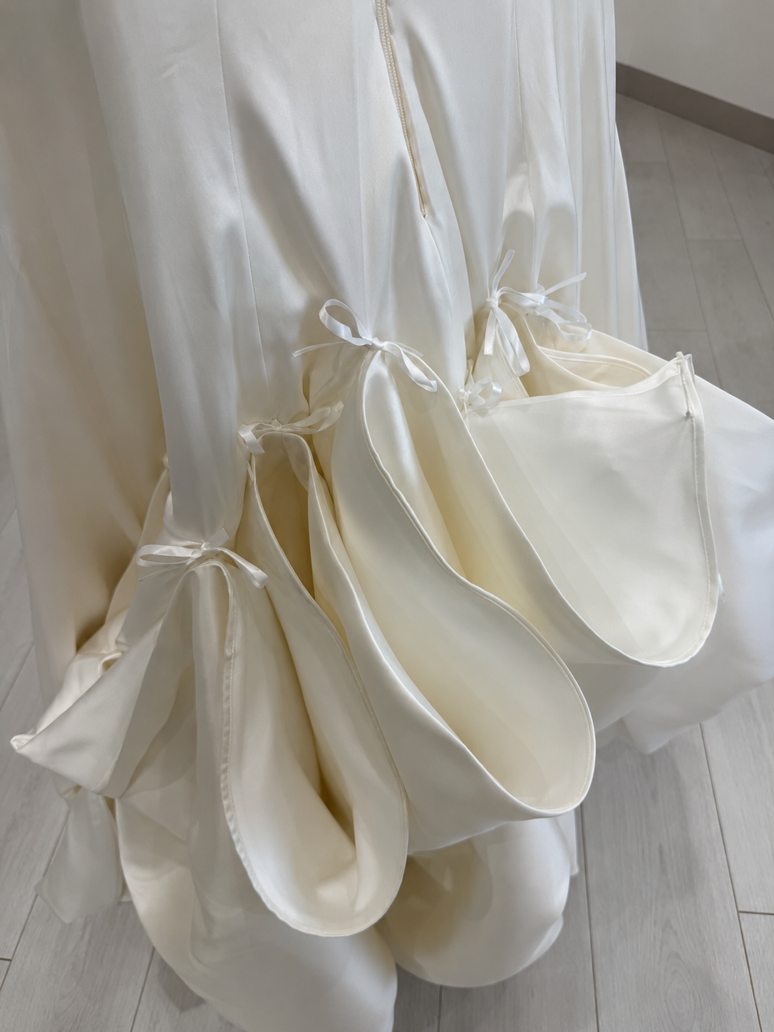 Close-up of ribbon-tied fabric folds forming a ballroom bustle