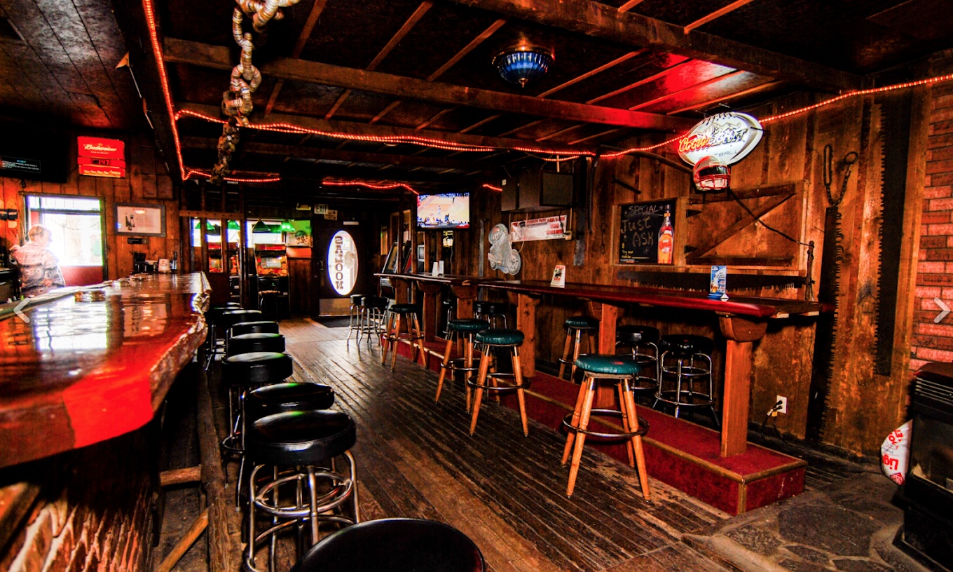 A bar with a lot of stools and tables in it.
