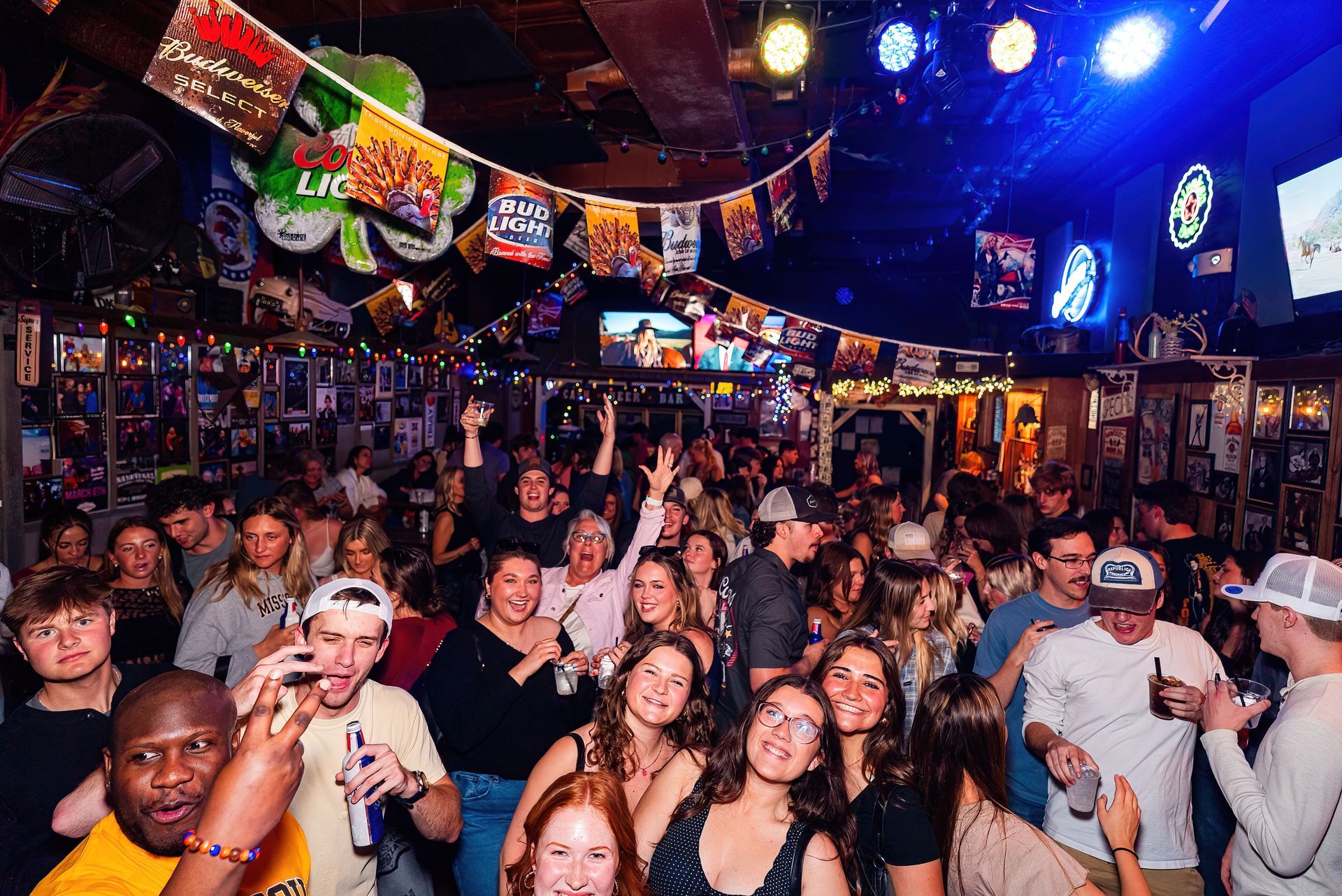 Crowded nightclub with people dancing, raised hands, and colorful lights