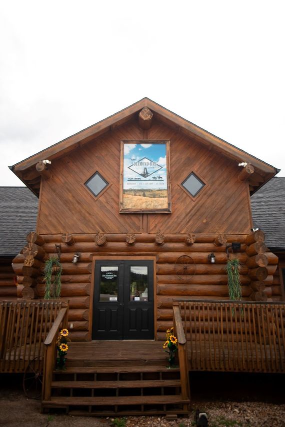 Log cabin-style building with a wooden porch and decorative sign above the entrance