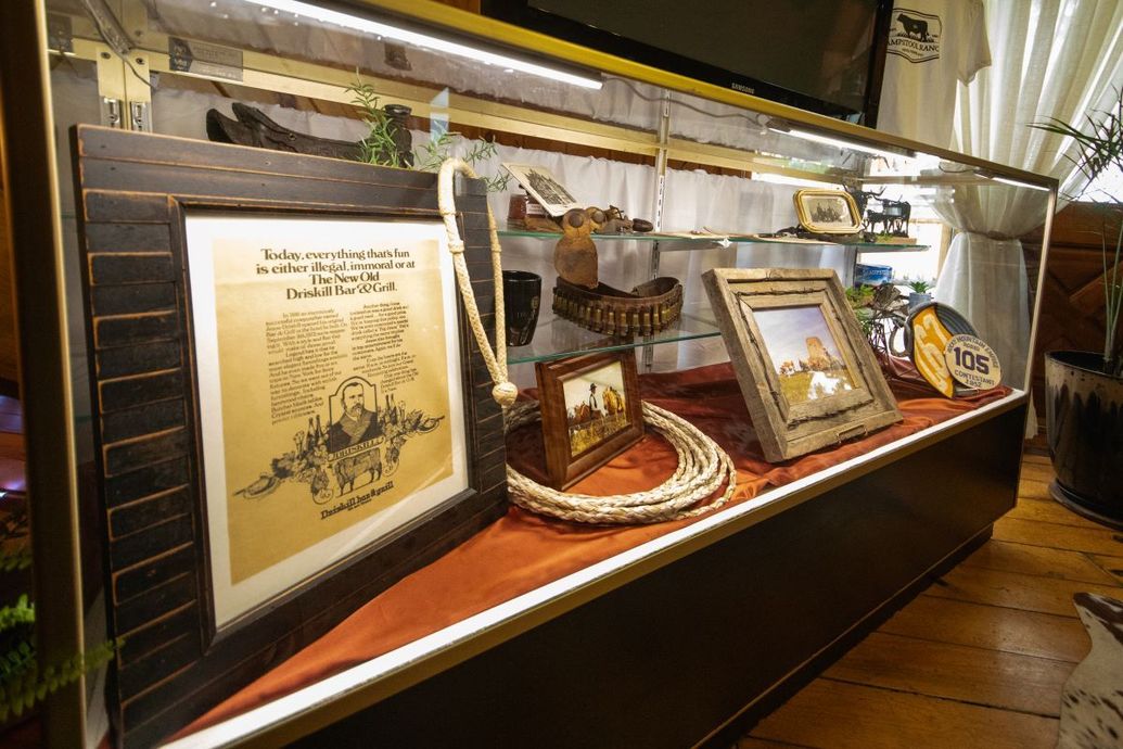 Glass display case with framed documents and artifacts along a wooden wall in a museum or gallery