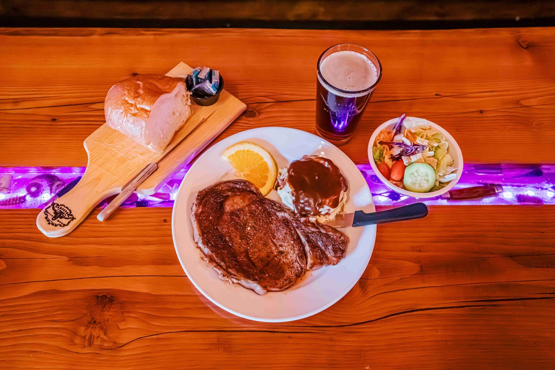 Breakfast spread on a wooden table with pancakes, toast, fruit, a coffee drink, and a small salad.
