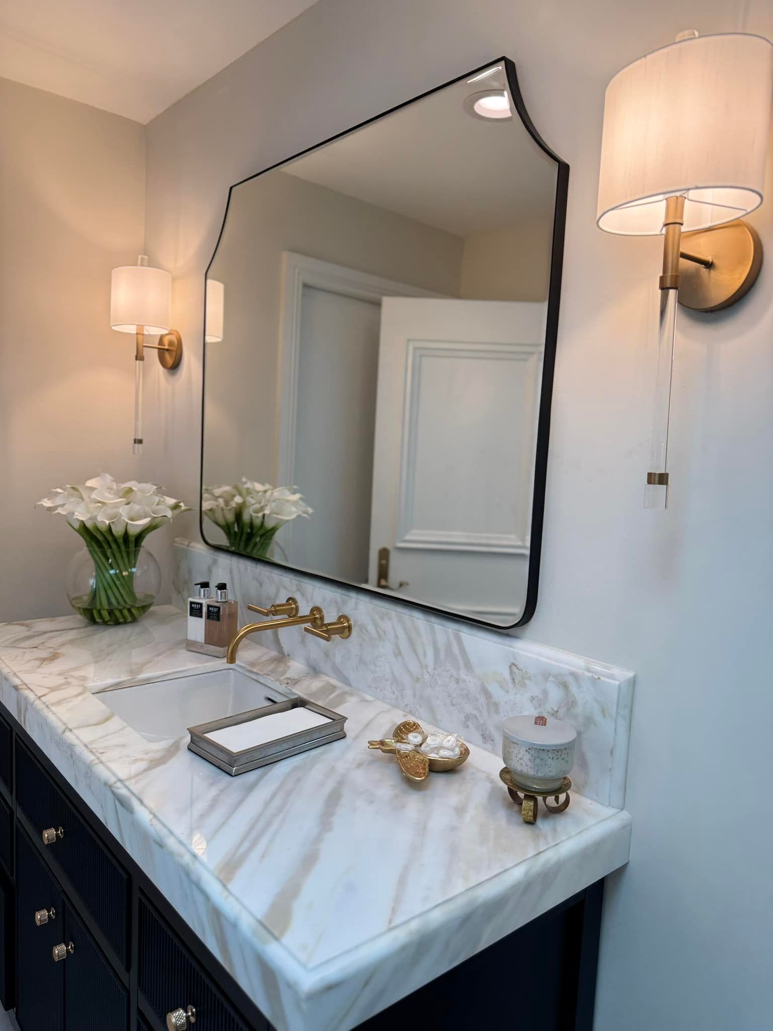 A bathroom with a sink , mirror and two lights.