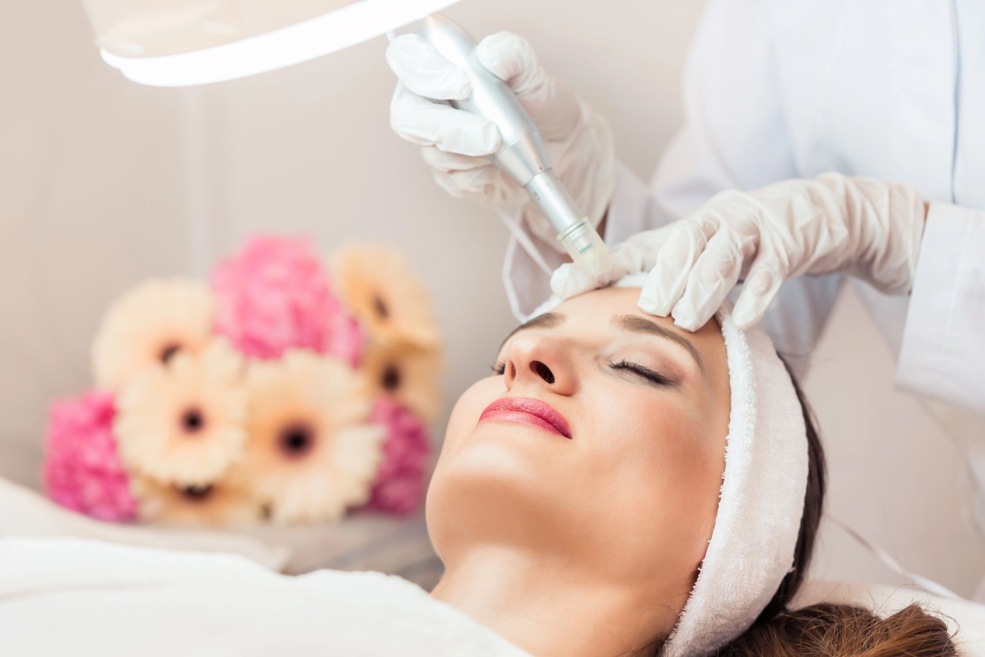 Donna che si sottopone a un trattamento viso sotto una luce intensa in una spa, con gli occhi chiusi.
