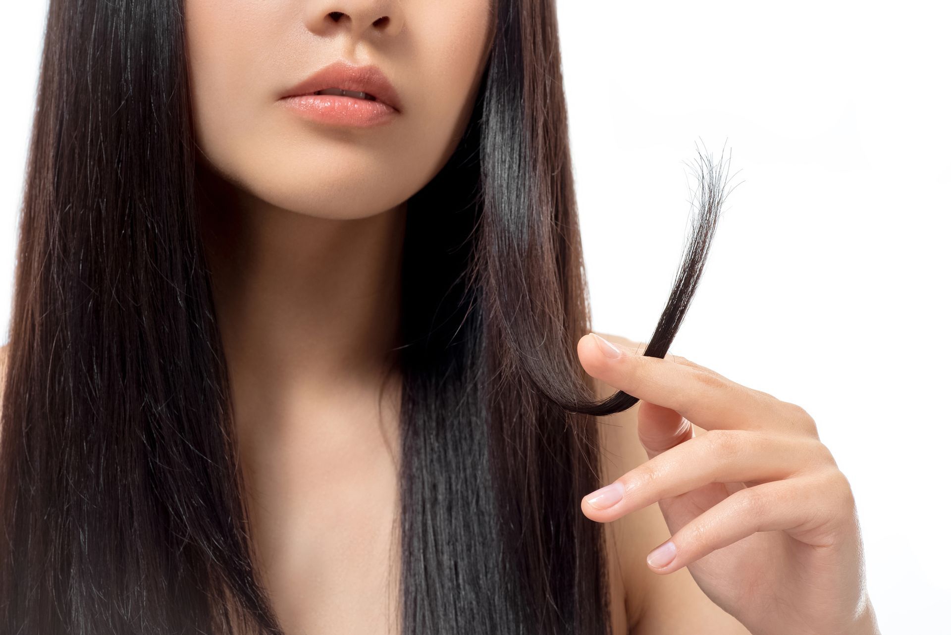 Donna che tiene in mano una ciocca di capelli con doppie punte su uno sfondo di capelli neri, sfondo bianco.