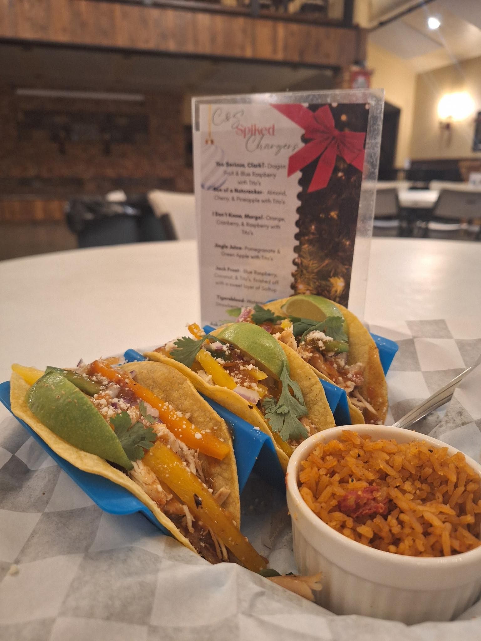 Tacos and a bowl of rice on a table, with a menu standing behind them.