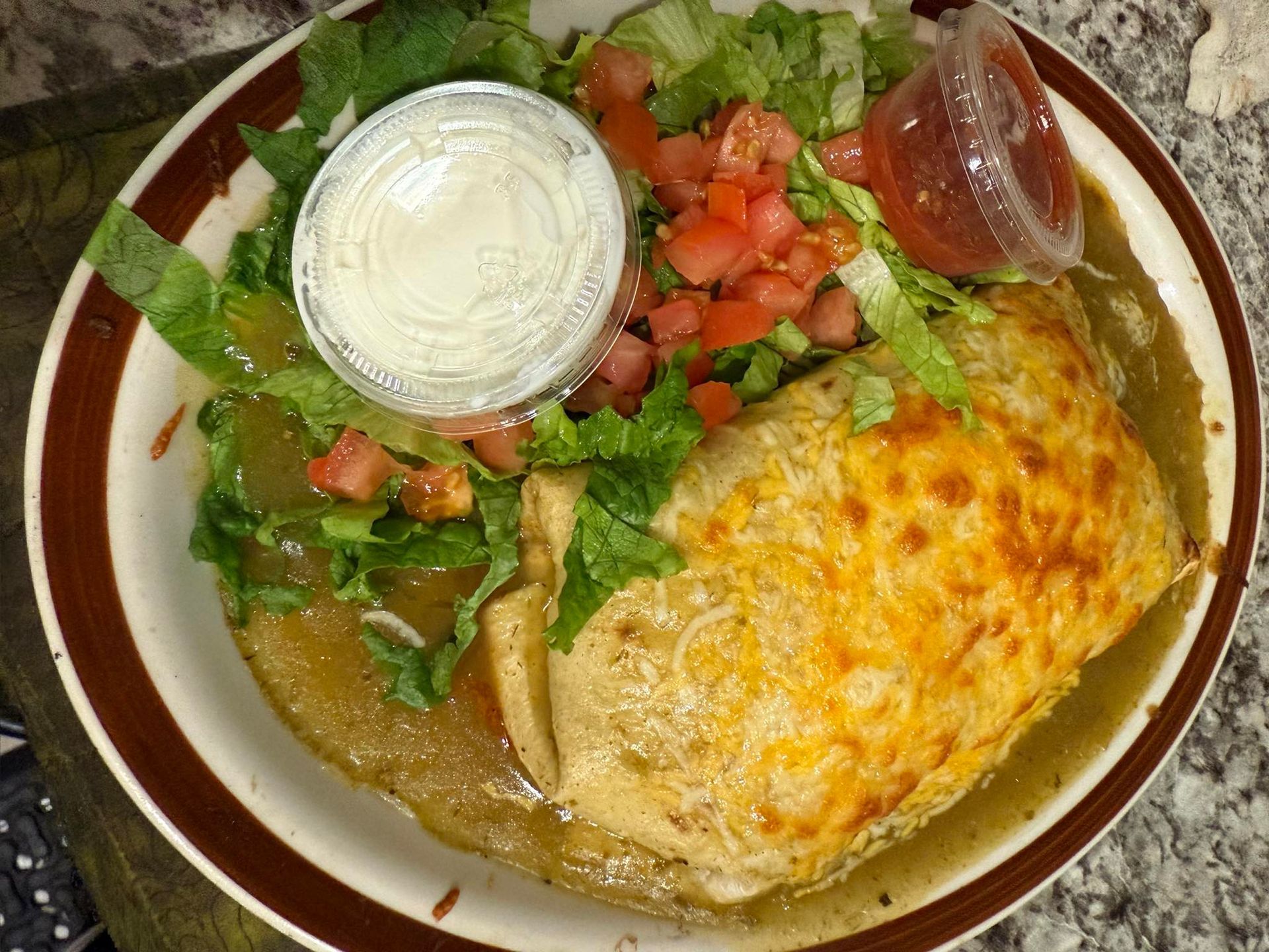 Mexican plate with enchiladas, rice, beans, lettuce, tomato, and sour cream