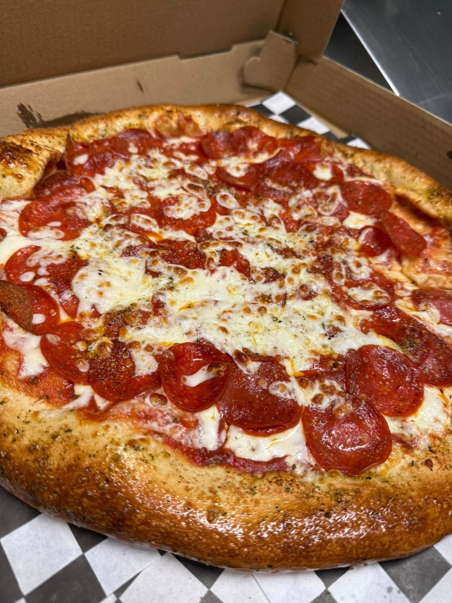 Pepperoni pizza in a cardboard box with a golden crust and melted cheese
