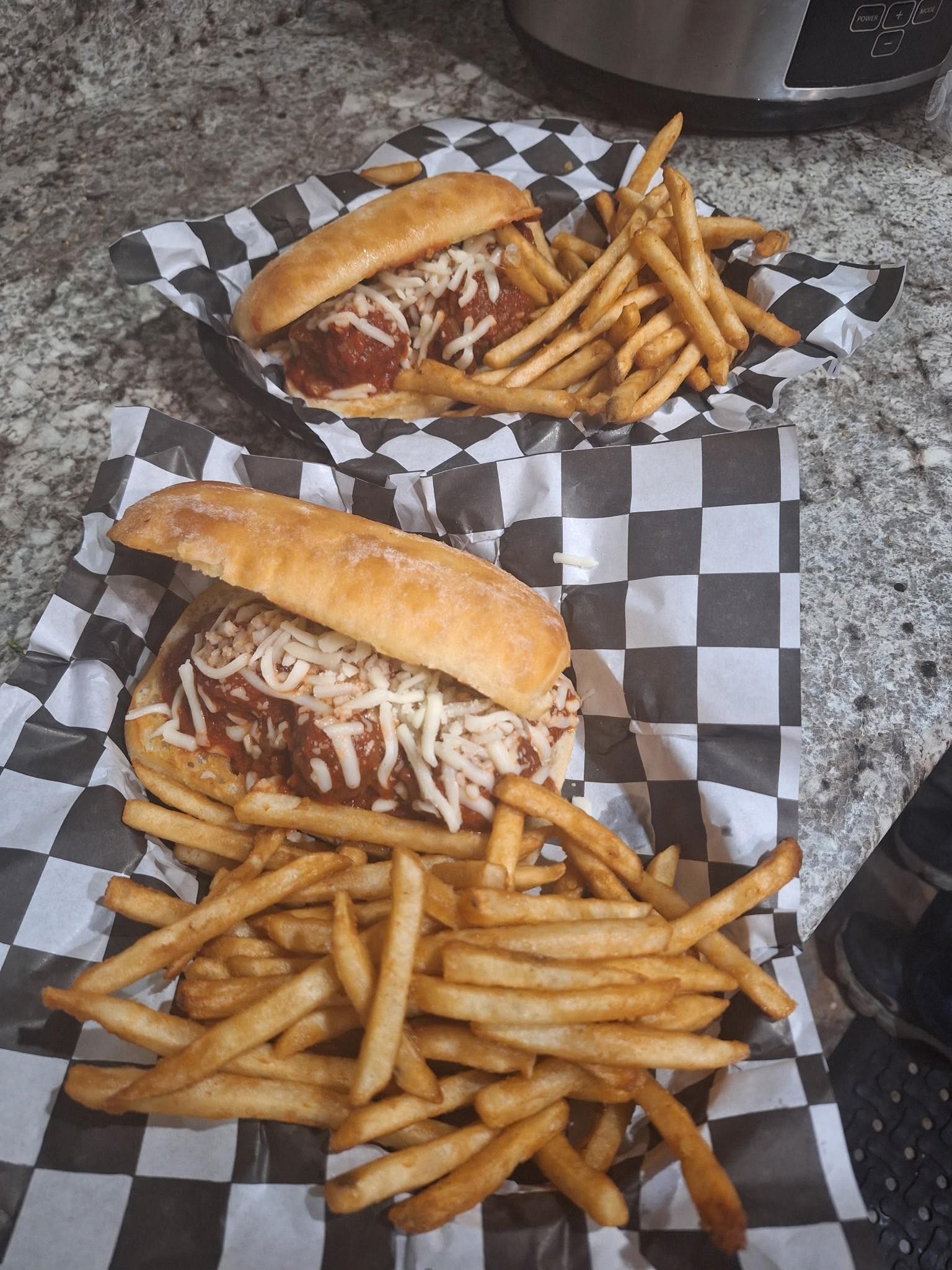 Two sandwiches and fries on checkered paper on a table