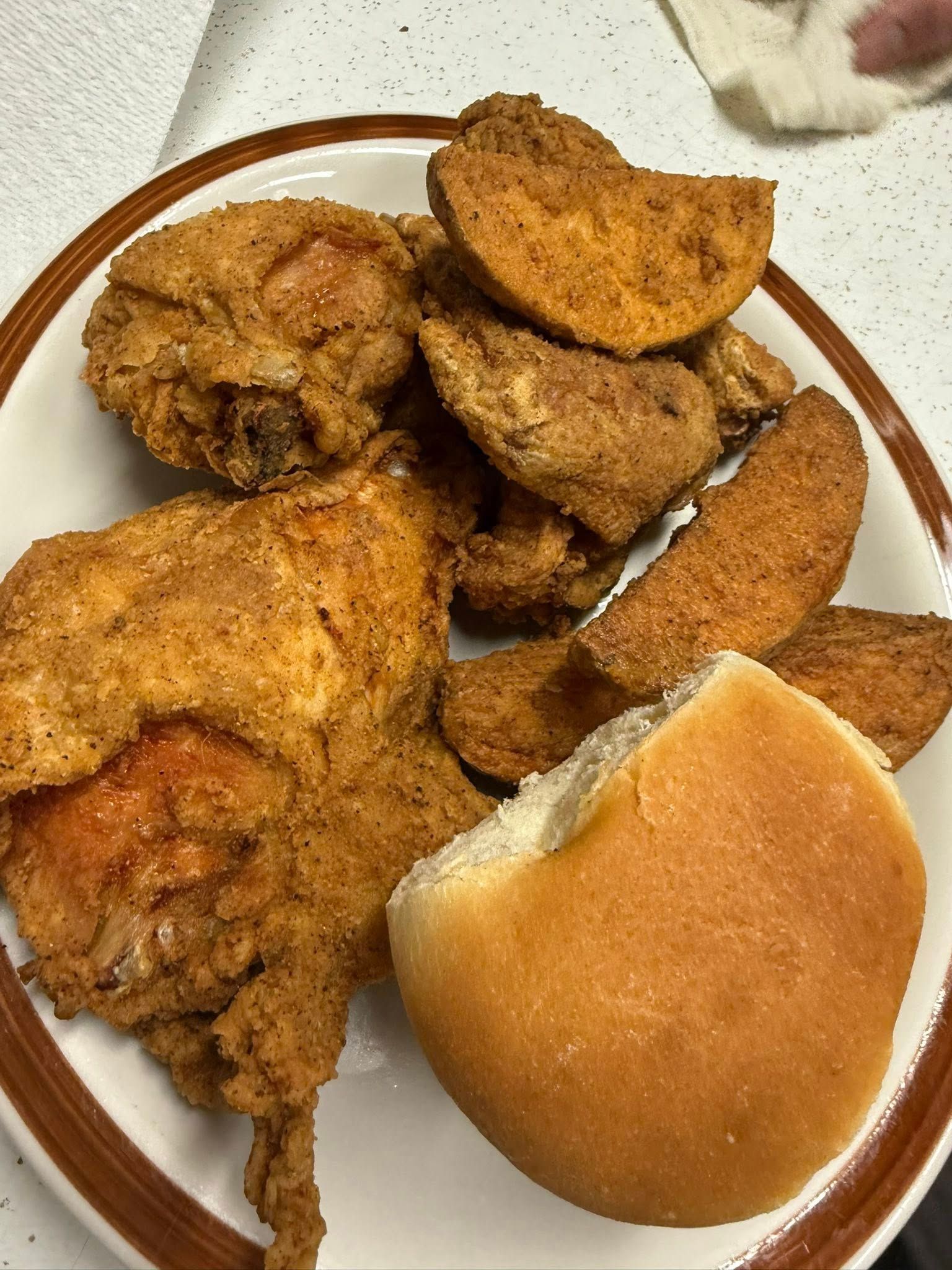 Plate of fried chicken and a dinner roll on a white dish.