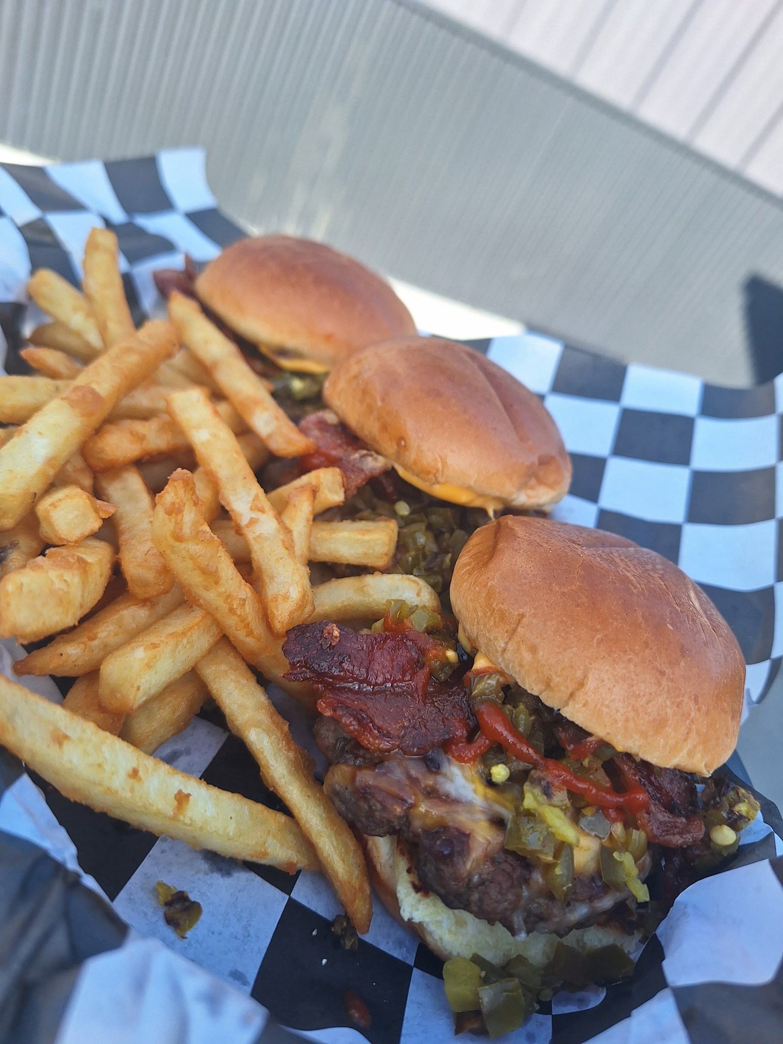 Two sliders with fries on black-and-white checkered paper tray
