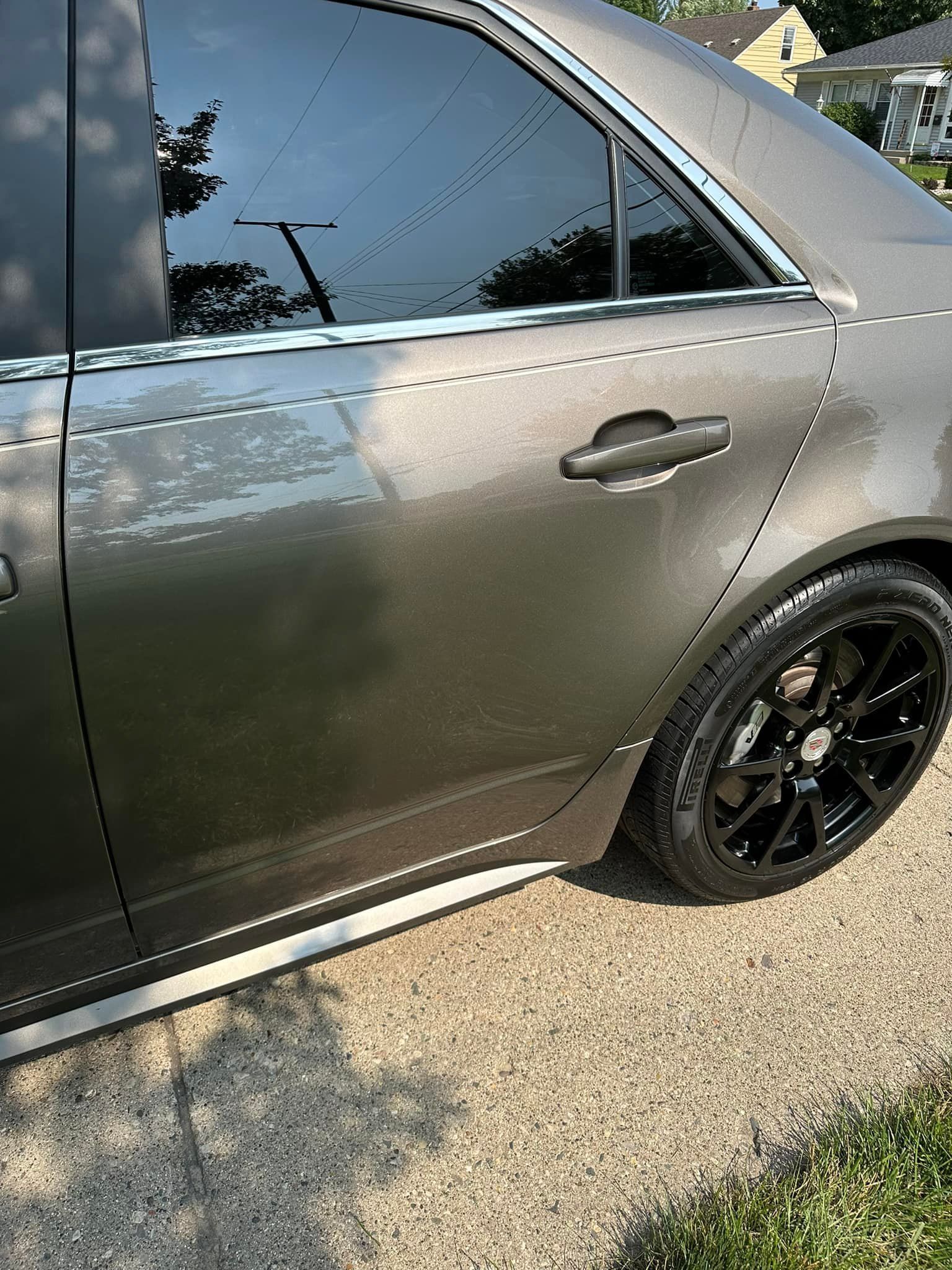 Gray sedan with black rims and tinted windows parked on a driveway.