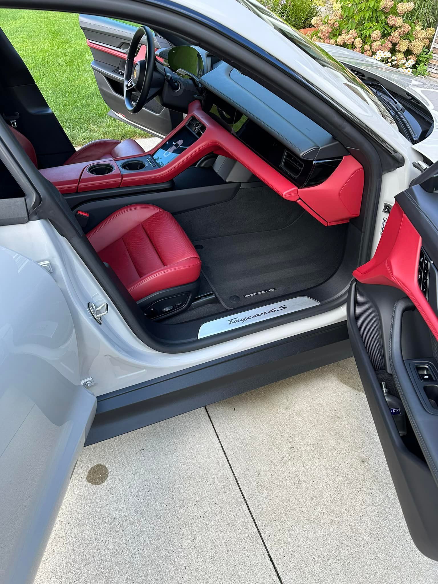 Silver Porsche Taycan with red interior; driver's door open.