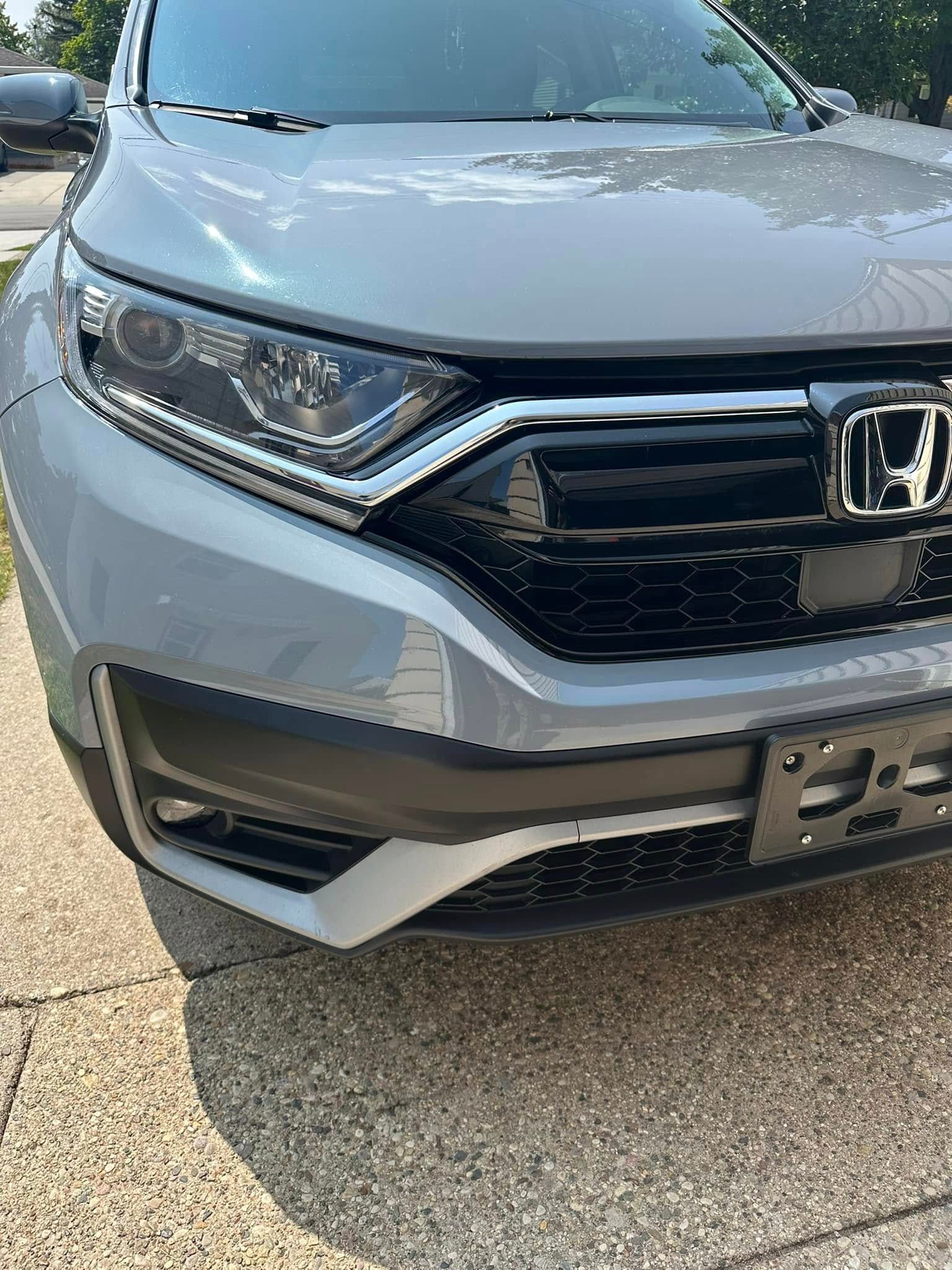 Gray Honda CRV front view, black grill, and license plate.