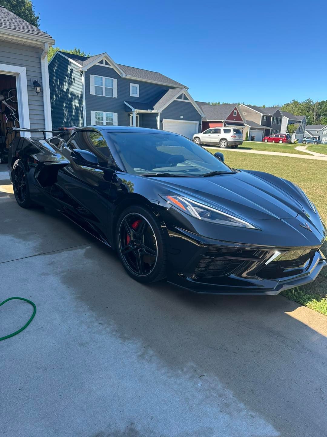 Black Corvette convertible parked in a driveway on a sunny day.