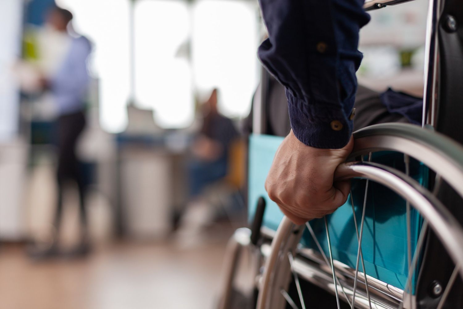 A man in a wheelchair is holding the handle of the wheel.