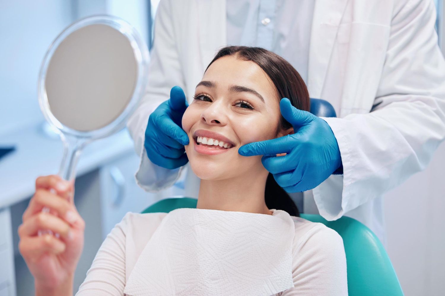 A woman is sitting in a dental chair while a dentist examines her teeth.