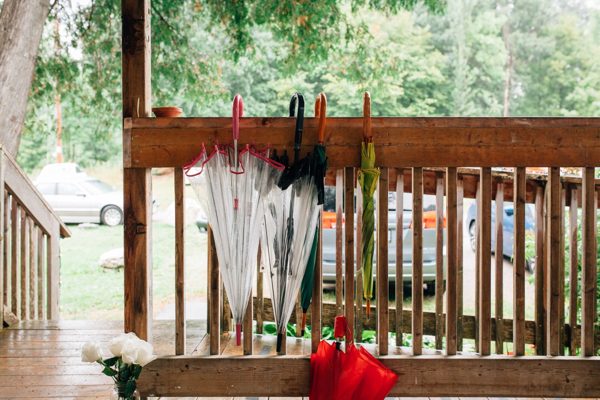 A wooden porch with umbrellas hanging on the railing.