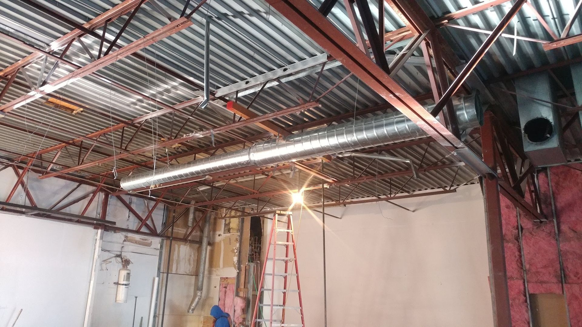 Wooden house frame under construction with roof trusses and workers inside