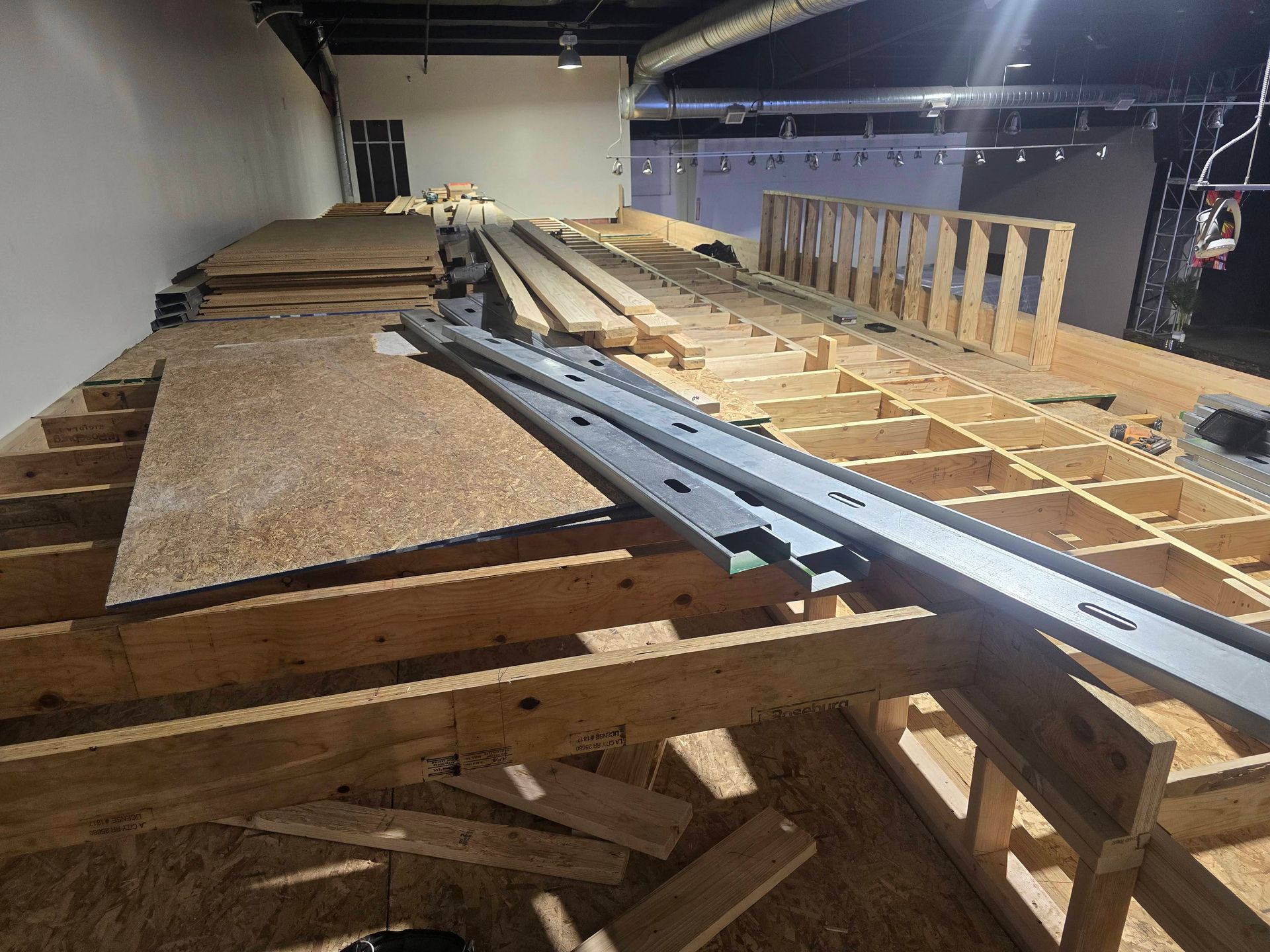 Wooden attic floor framing with long metal rails and plywood panels in an unfinished interior space