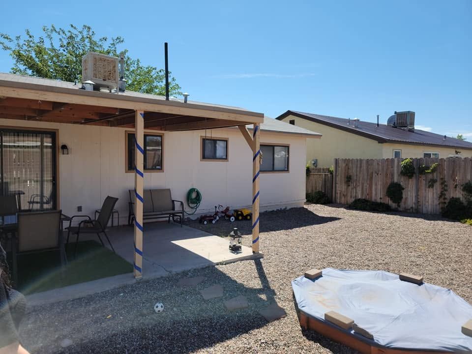Back patio with gravel yard, covered porch, and a small above-ground pool under a blue sky