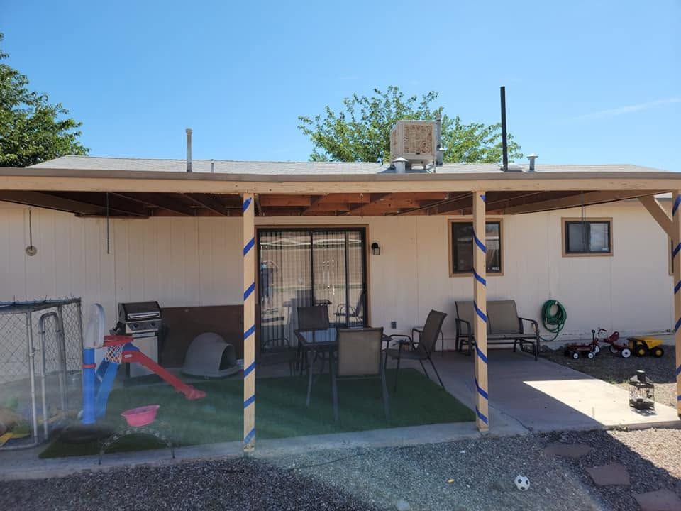 Patio with patio furniture, grill, and play area under a covered porch beside a beige house.