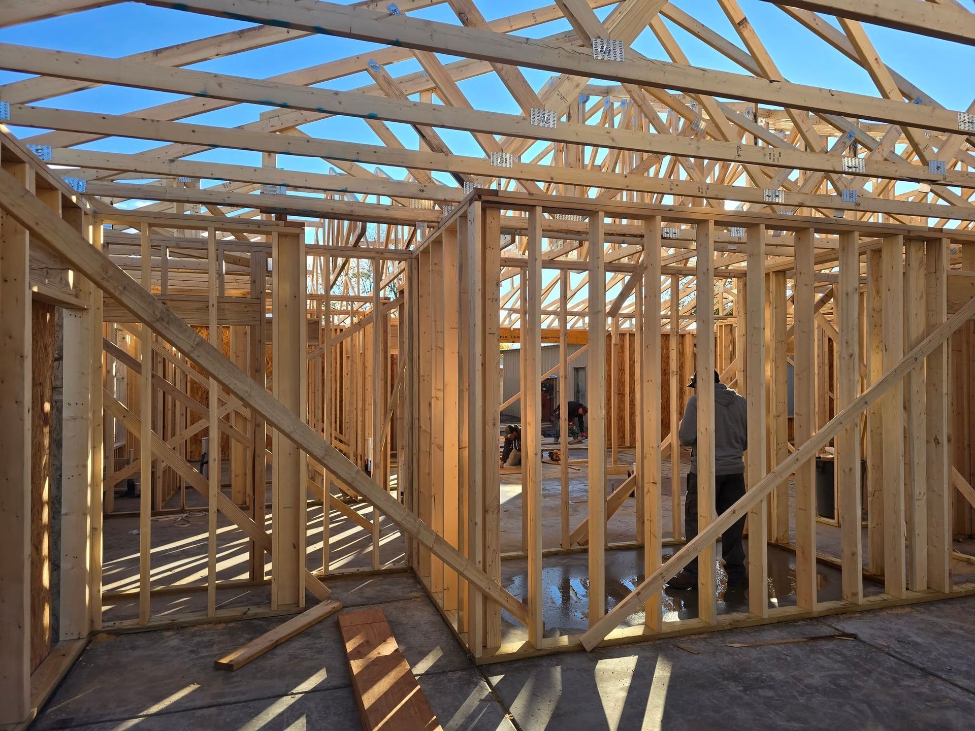 Wooden house frame under construction with roof trusses and workers inside