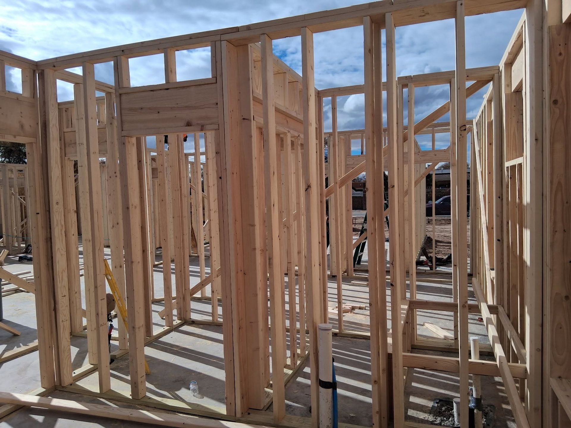Wood-framed house under construction with exposed studs and a partially framed roof