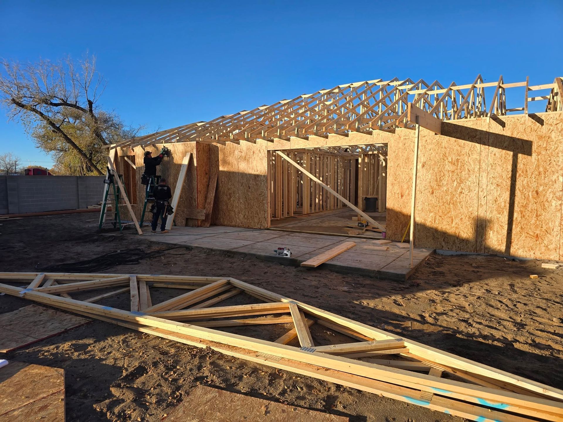 Construction site with framed wooden house walls and roof trusses under installation